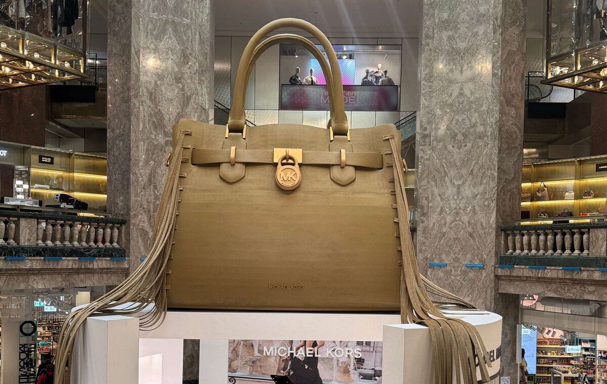 Sac géant Michael Kors suspendu au-dessus d’un pop-up de grand magasin